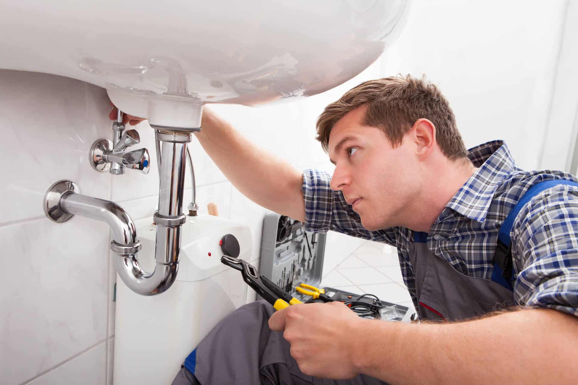 Técnico realizando reparo hidráulico em banheiro moderno